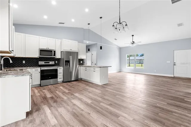 a large kitchen with cabinets wooden floor and stainless steel appliances