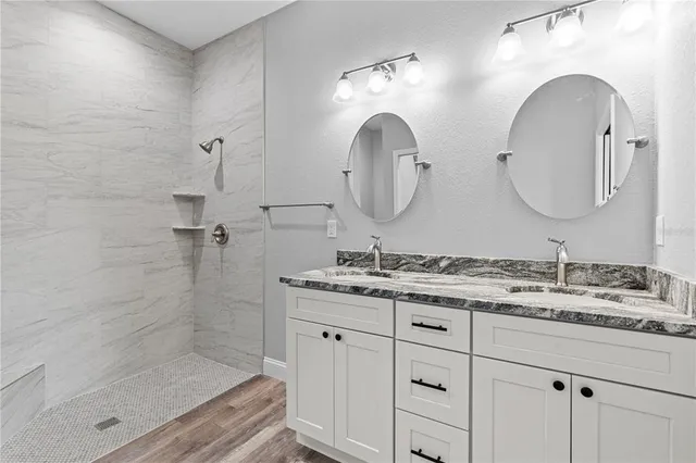 a bathroom with a granite countertop sink a mirror and shower