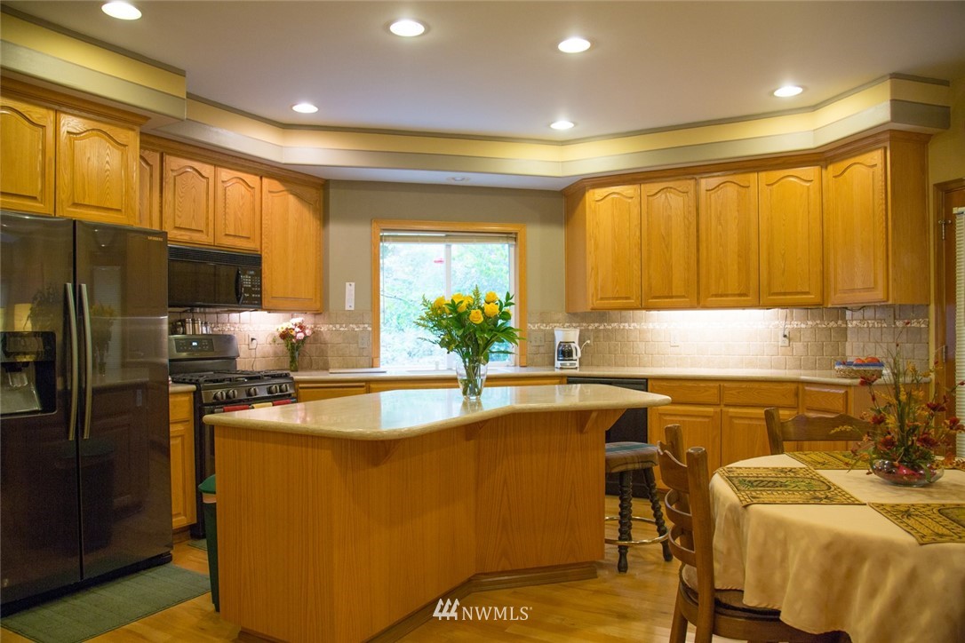 22705 Peter Grubb Road Southeast Renton, WA 98058 - Photo 5 of 40 a kitchen with stainless steel appliances granite countertop a sink a stove and a refrigerator