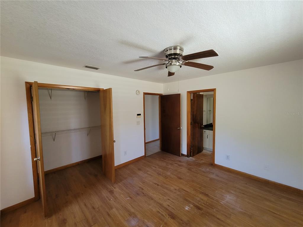 37515 Phelps Road Zephyrhills, FL 33541 - Photo 18 of 25 a view of an empty room with wooden floor and a ceiling fan