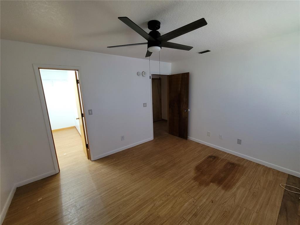 37515 Phelps Road Zephyrhills, FL 33541 - Photo 23 of 25 an empty room with wooden floor and a ceiling fan