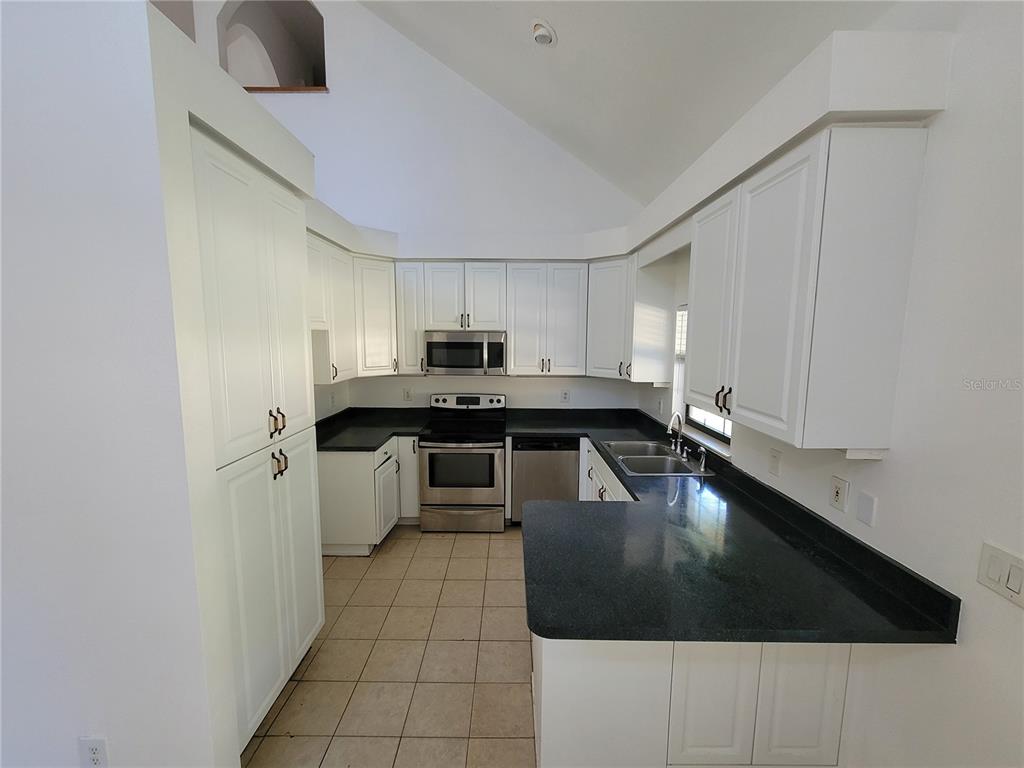 37515 Phelps Road Zephyrhills, FL 33541 - Photo 9 of 25 a kitchen with stainless steel appliances a sink a stove top oven a counter space and cabinets