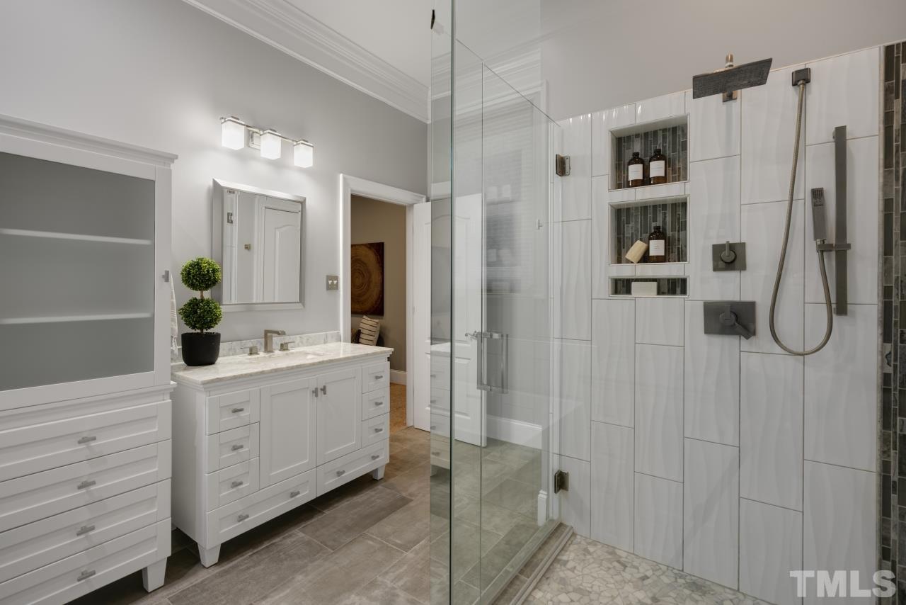 5909 Greenevers Drive Raleigh, NC 27613 - Photo 15 of 30 a bathroom with a double vanity sink a mirror a shower and vanity