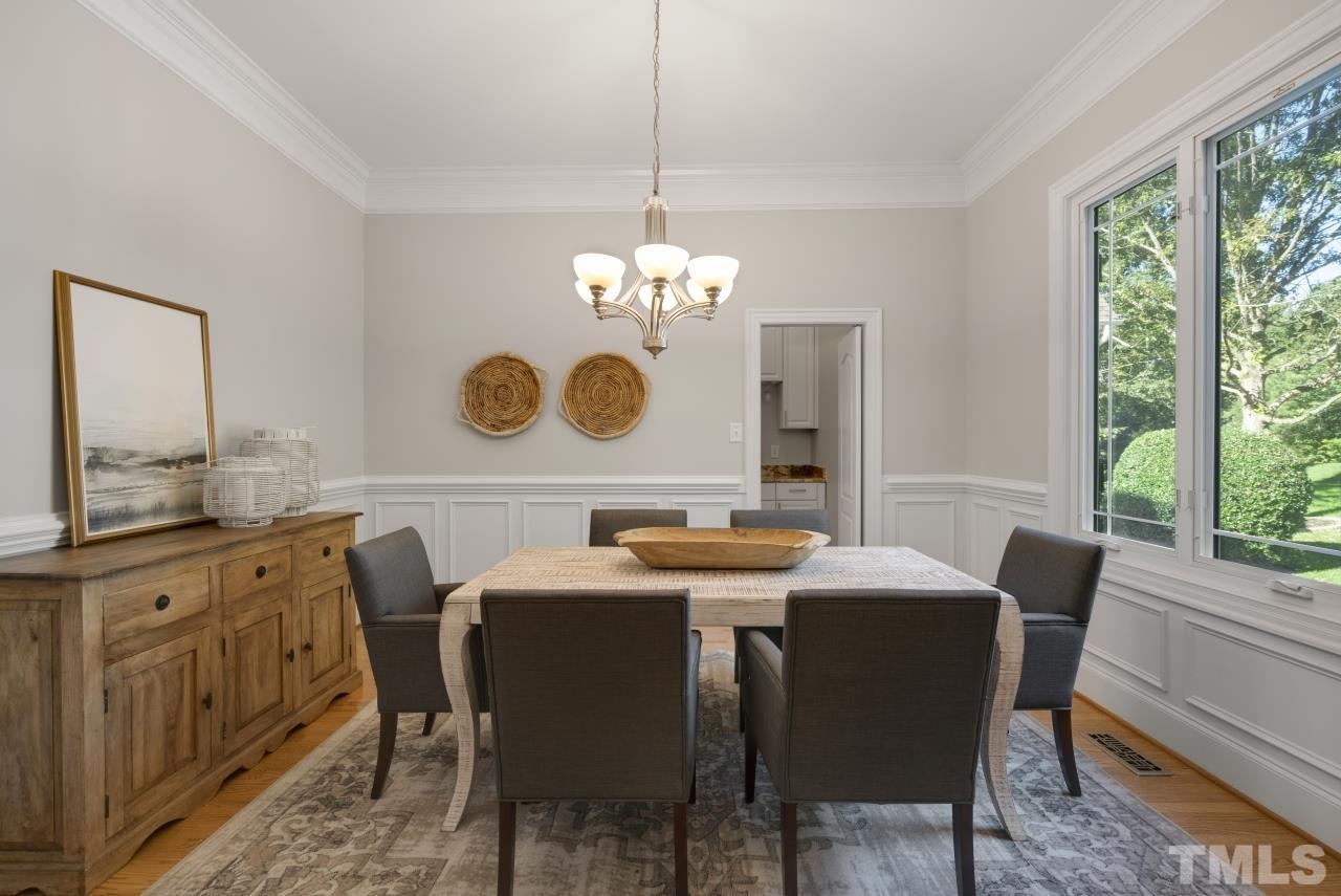 5909 Greenevers Drive Raleigh, NC 27613 - Photo 5 of 30 a dining room with wooden floor a chandelier a wooden table and chairs