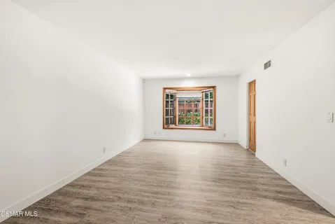 an empty room with wooden floor and windows