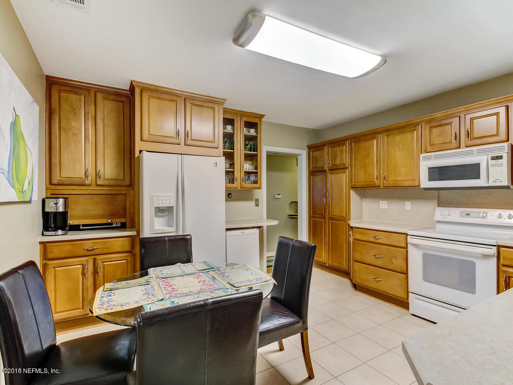 1526 Somerville Road Jacksonville, FL 32207 - Photo 12 of 30 a kitchen with stainless steel appliances wooden floor dining table and chairs