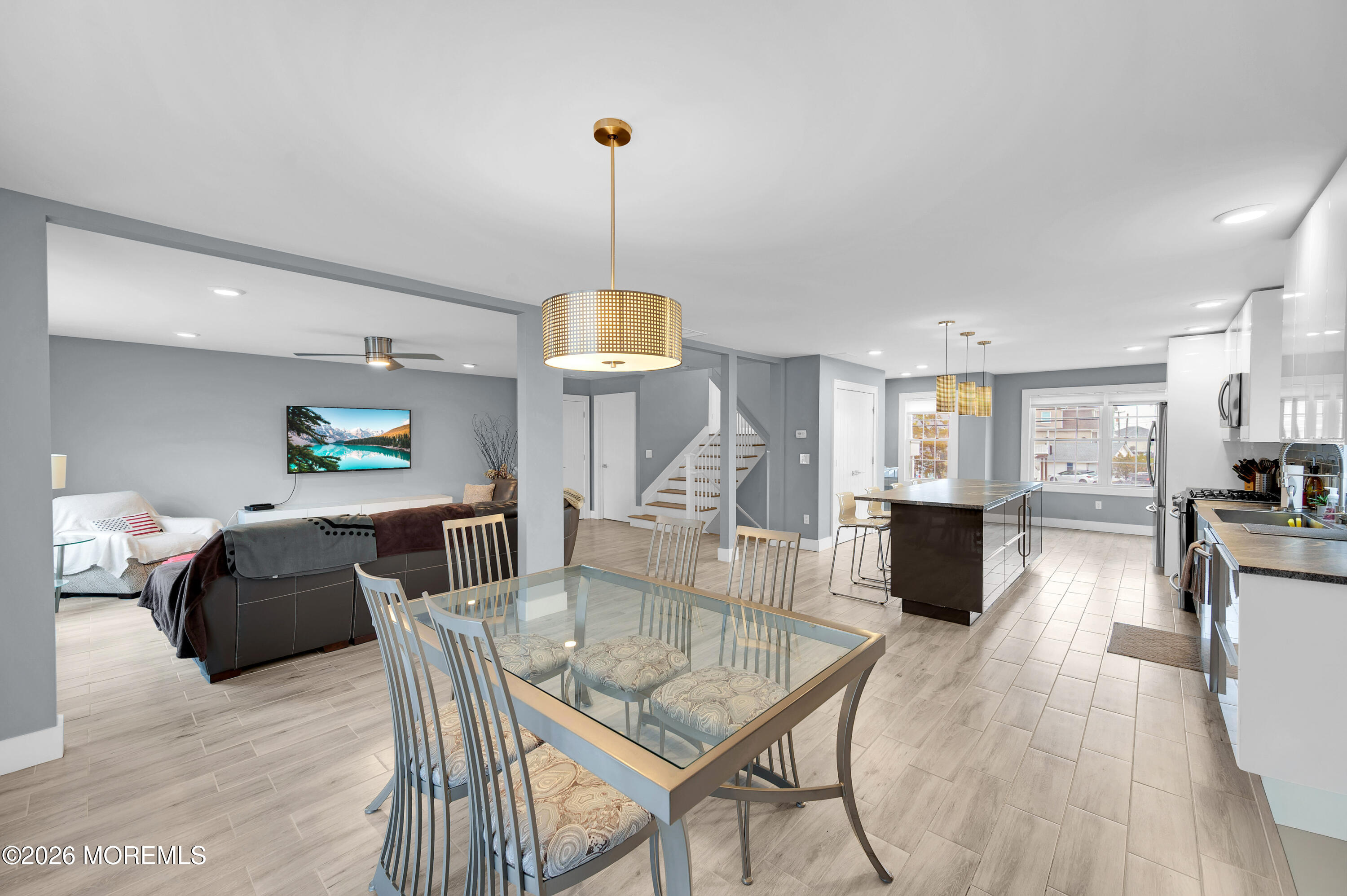 97 Bay View Drive Brick, NJ 08723 - Photo 29 of 65 a view of a dining room and livingroom with furniture wooden floor a rug a flat screen tv a painting and a chandelier