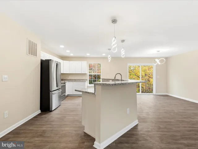 a kitchen with stainless steel appliances granite countertop a stove a refrigerator and a white cabinets