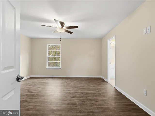 an empty room with wooden floor fan and windows