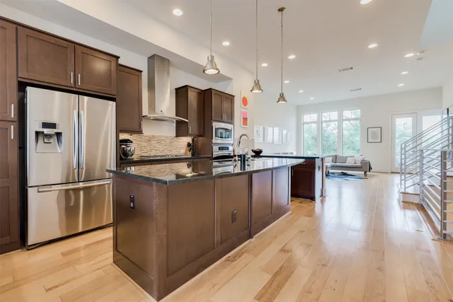 a kitchen with stainless steel appliances kitchen island granite countertop a refrigerator a oven a sink and a refrigerator