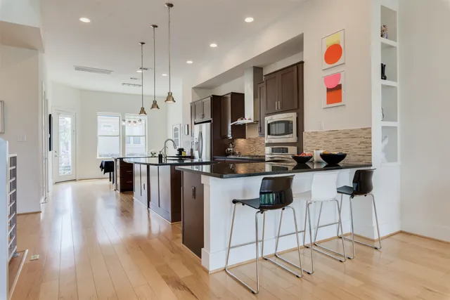 a kitchen with stainless steel appliances kitchen island granite countertop a stove a sink and a refrigerator