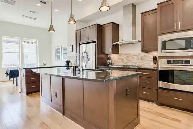 a kitchen with stainless steel appliances granite countertop a sink a stove and a wooden floors