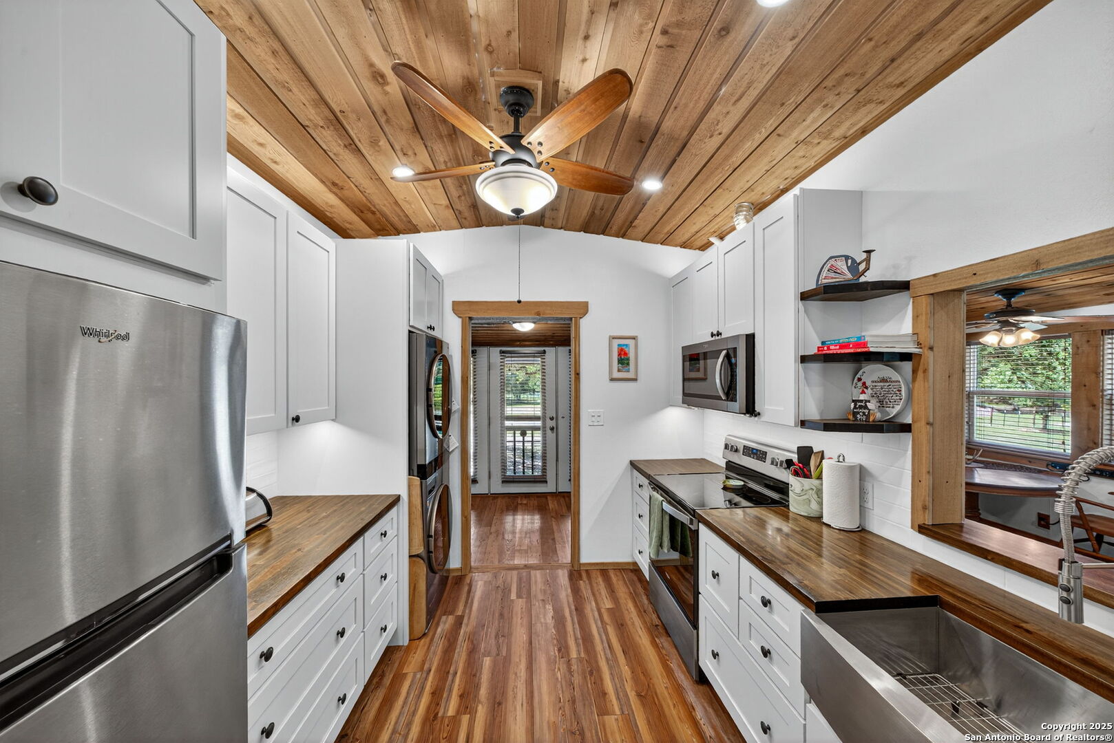 924 Wagon Creek Road Bandera, TX 78003 - Photo 11 of 33 a kitchen with stainless steel appliances a refrigerator a stove a sink dishwasher and wooden cabinets with wooden floor