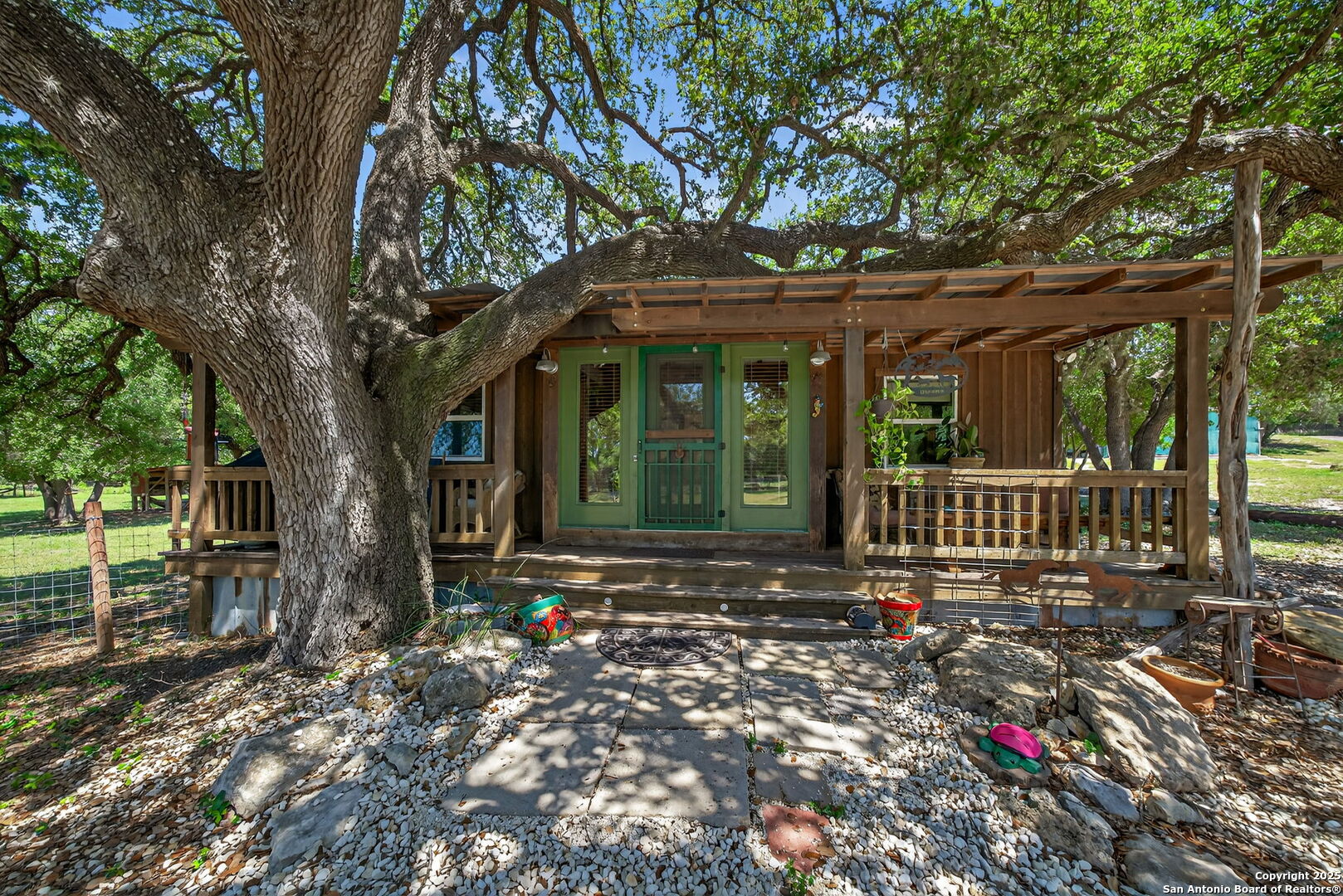 924 Wagon Creek Road Bandera, TX 78003 - Photo 4 of 33 a view of a house with a small yard and a large tree