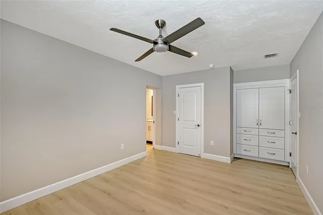 a view of empty room with wooden floor and ceiling fan