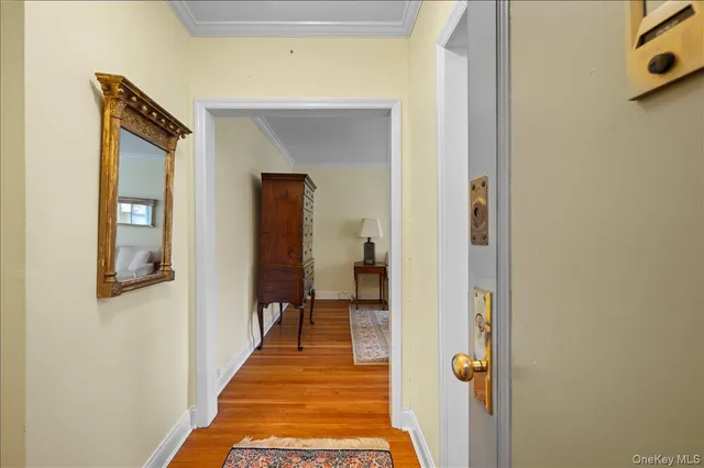 a view of a hallway with wooden floor and a bathroom