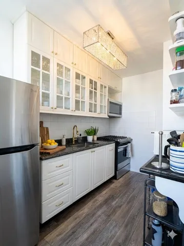 a kitchen with stainless steel appliances granite countertop a refrigerator a stove a sink dishwasher a microwave oven with white cabinets and wooden floor