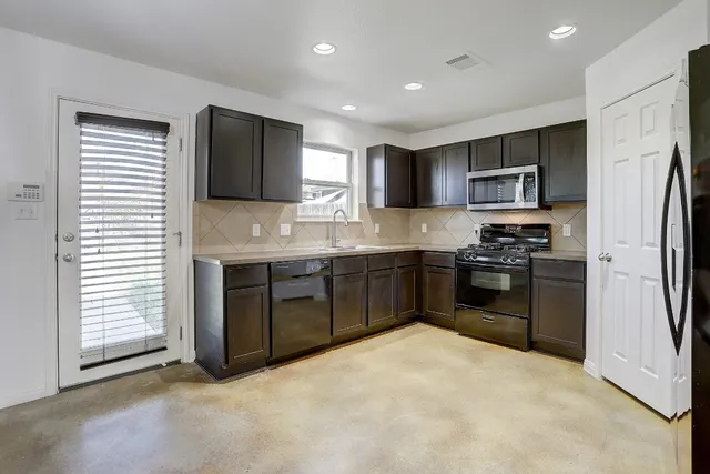 a kitchen with stainless steel appliances kitchen island granite countertop a refrigerator stove top oven and sink