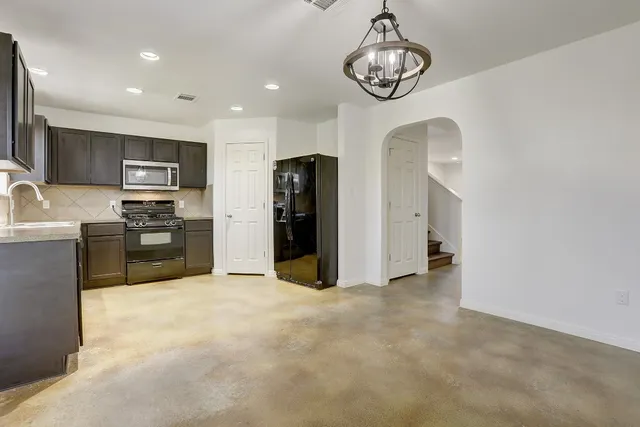 a view of a kitchen with stainless steel appliances granite countertop a refrigerator a stove top oven a sink and dishwasher