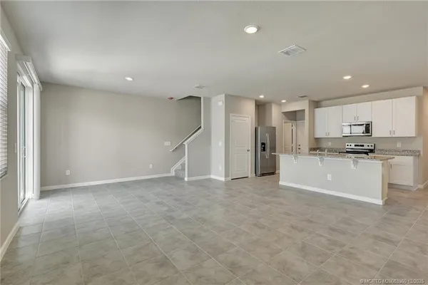 a view of kitchen with refrigerator and white cabinets