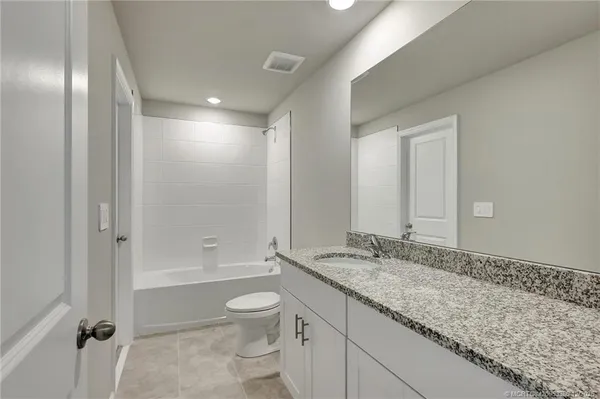 a bathroom with a granite countertop sink a toilet and shower