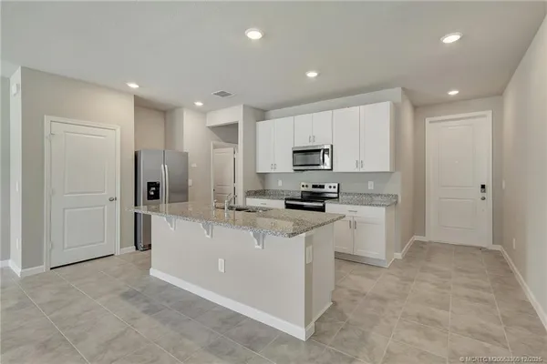 a kitchen with white cabinets and refrigerator