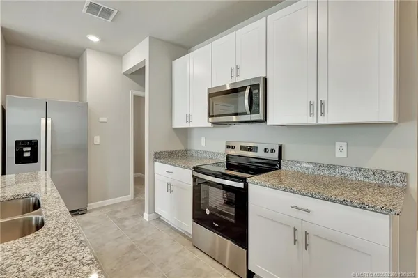 a kitchen with granite countertop a sink stove and refrigerator
