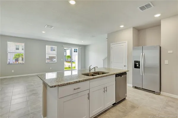 a kitchen with granite countertop kitchen island stainless steel appliances a sink stove and refrigerator