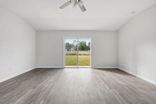 a view of an empty room with a window and wooden floor