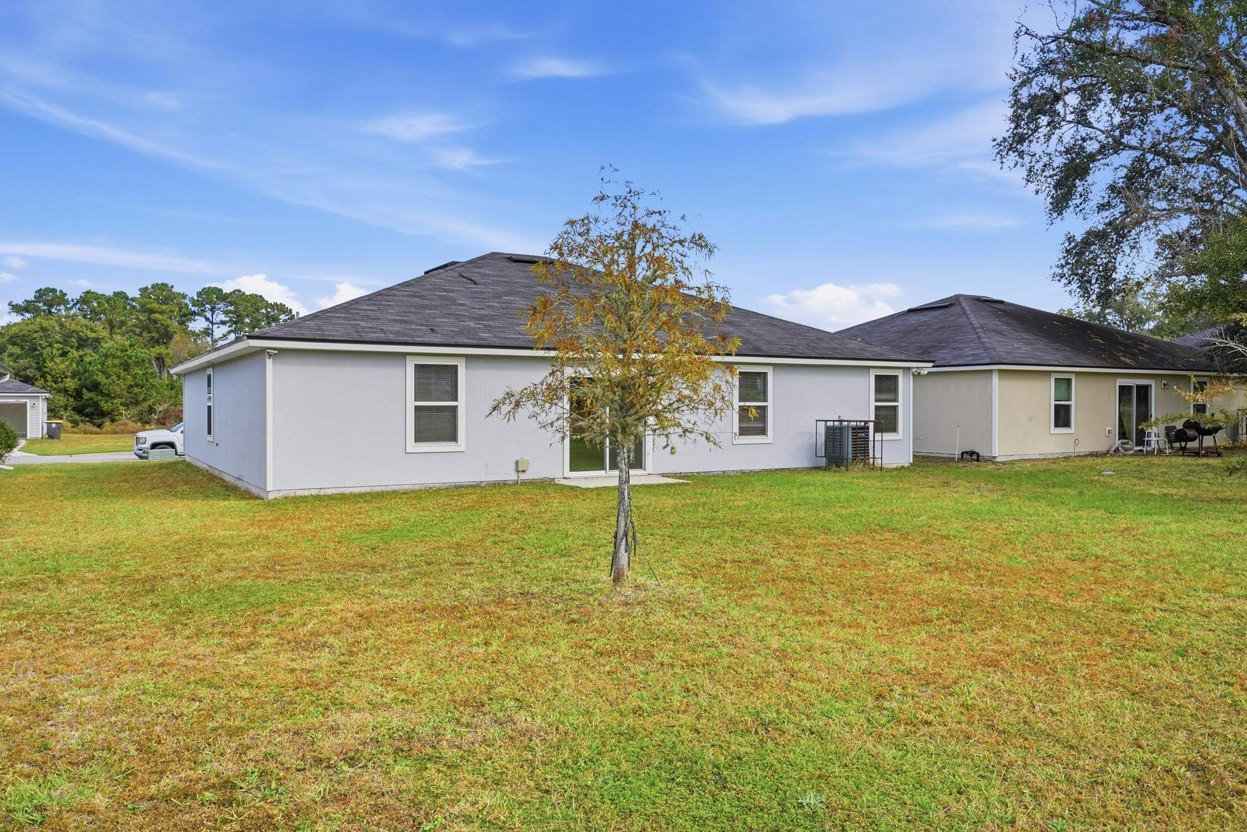8772 Kaye Lane Jacksonville, FL 32244 - Photo 23 of 35 Rear view of house featuring a lawn and stucco siding