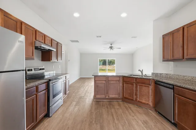 a kitchen with stainless steel appliances granite countertop wooden cabinets a stove top oven a sink and dishwasher