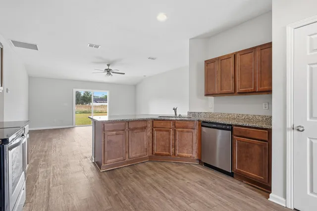 a kitchen with stainless steel appliances granite countertop a stove a sink and a refrigerator with wooden floors