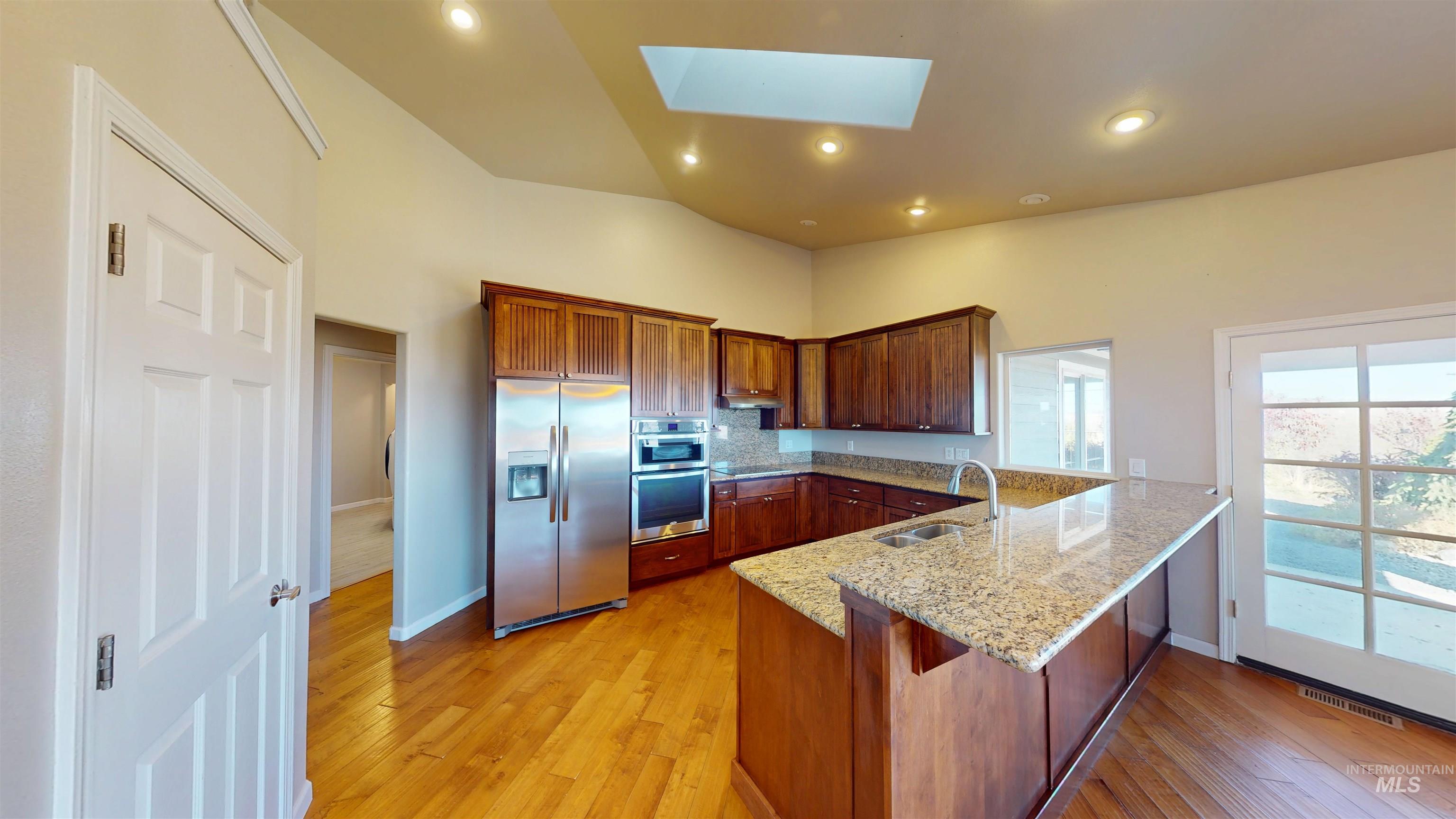 1030 Reams Road Moscow, ID 83843 - Photo 13 of 50 Kitchen featuring a peninsula, appliances with stainless steel finishes, a skylight, light stone counters, and light wood-style floors
