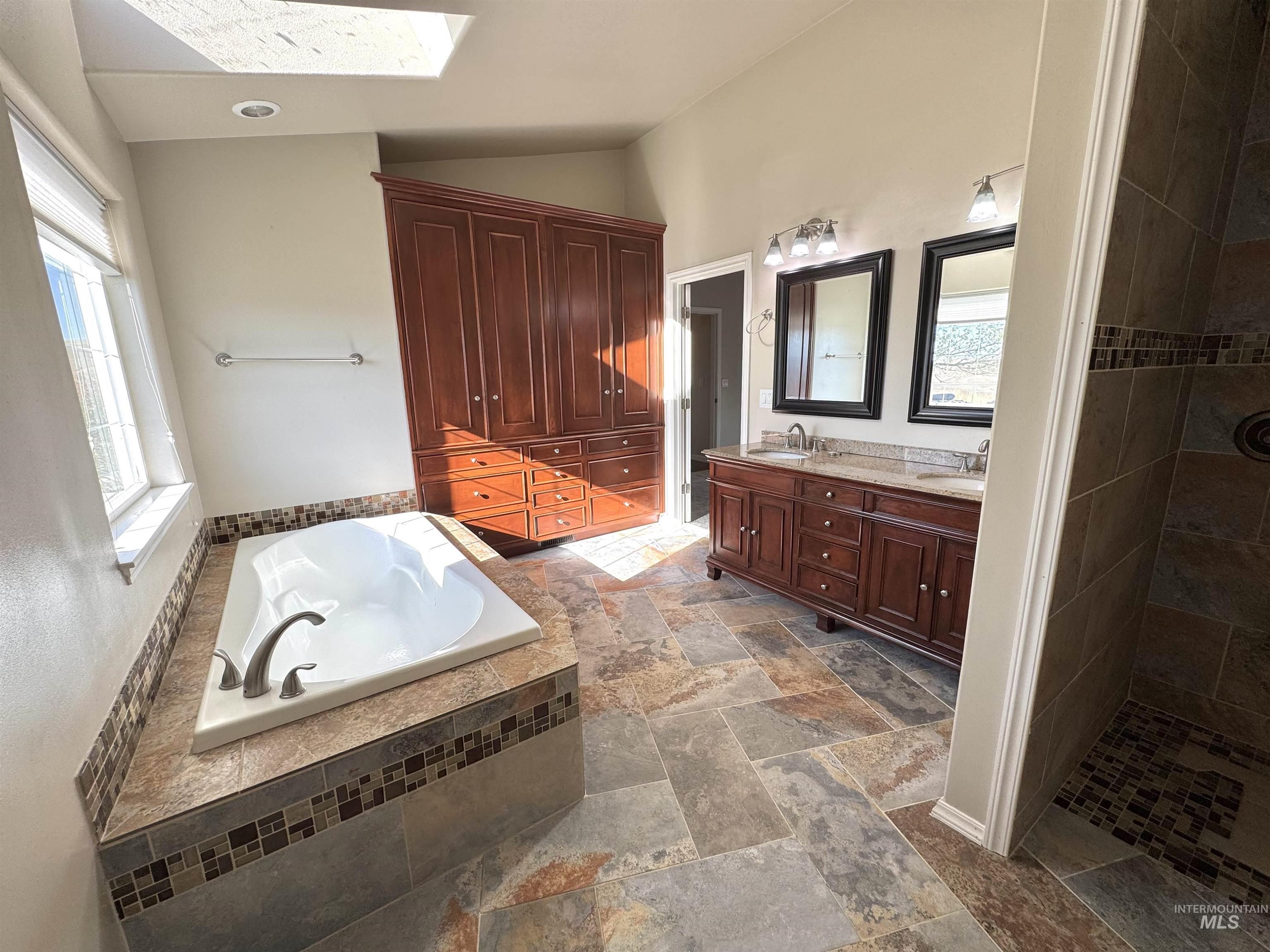 1030 Reams Road Moscow, ID 83843 - Photo 21 of 50 Bathroom featuring double vanity, a bath, walk in shower, lofted ceiling, and stone tile floors