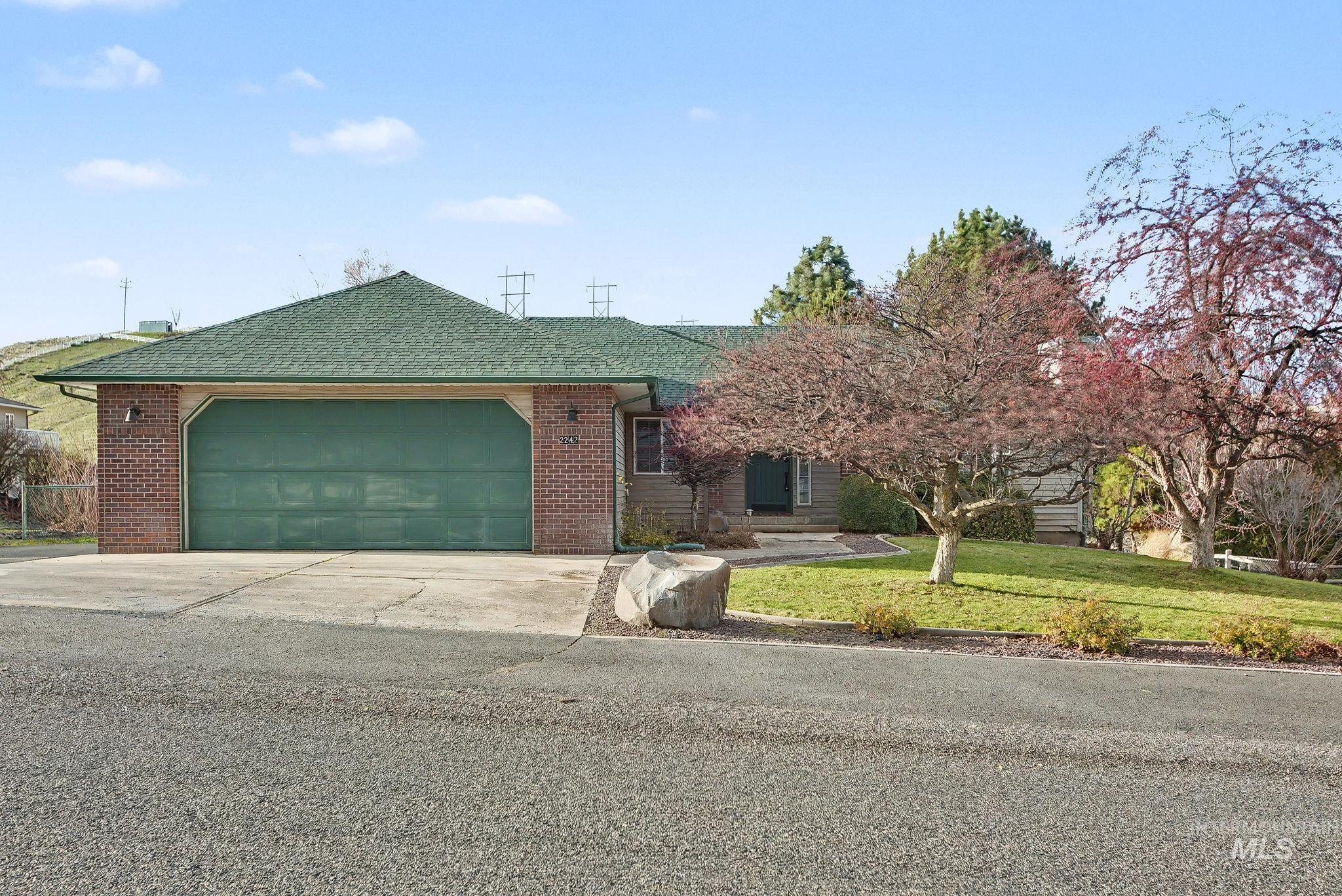 2242 Chukar Lane Clarkston, WA 99403 - Photo 37 of 41 Ranch-style home with roof with shingles, an attached garage, driveway, a front lawn, and brick siding