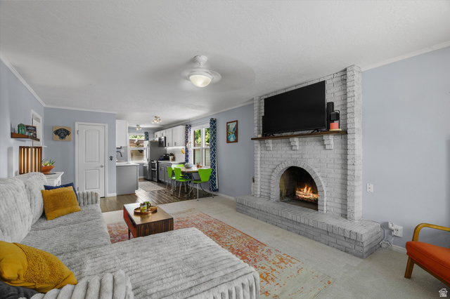 961 33rd Street Ogden, UT 84403 - Photo 7 of 39 Living area featuring a painted brick fireplace with a wood mantle, light blue walls, and a ceiling fan