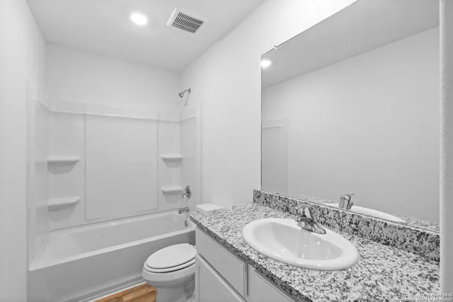 a bathroom with a granite countertop sink a toilet and shower