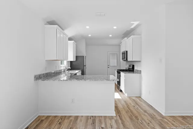 a kitchen with a sink a stove cabinets and wooden floor