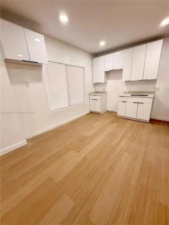 a kitchen with white cabinets and wooden floors