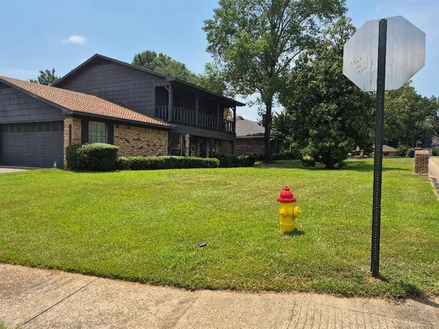a view of a house with a yard potted plants and a bench