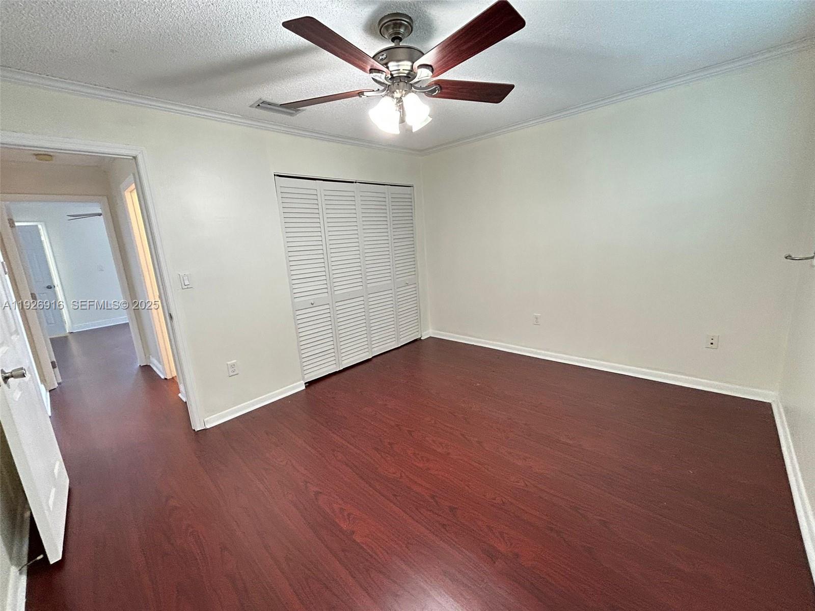 13444 Southwest 62nd Street, Unit 104F Miami, FL 33183 - Photo 32 of 40 an empty room with wooden floor and fan