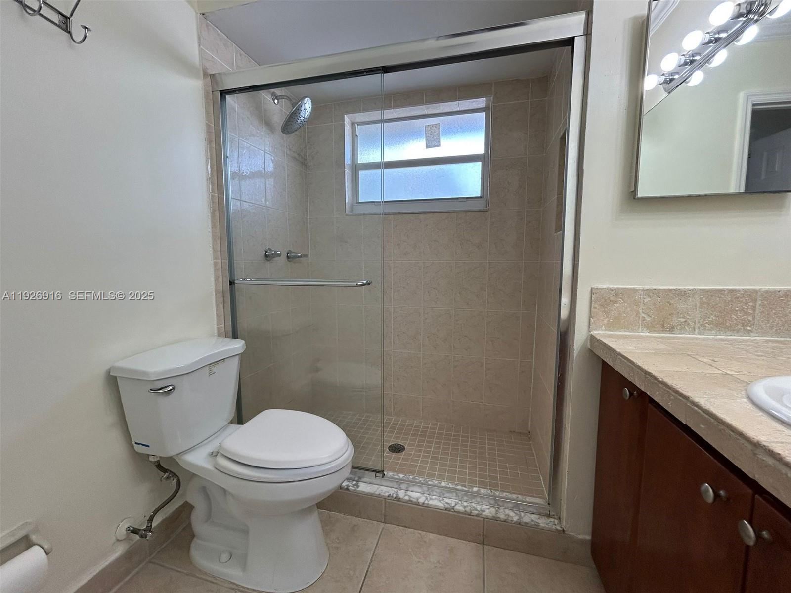 13444 Southwest 62nd Street, Unit 104F Miami, FL 33183 - Photo 33 of 40 a bathroom with a granite countertop toilet a sink and shower