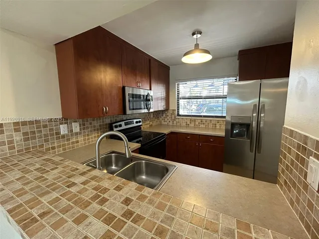 a kitchen with granite countertop a sink stainless steel appliances and a counter space