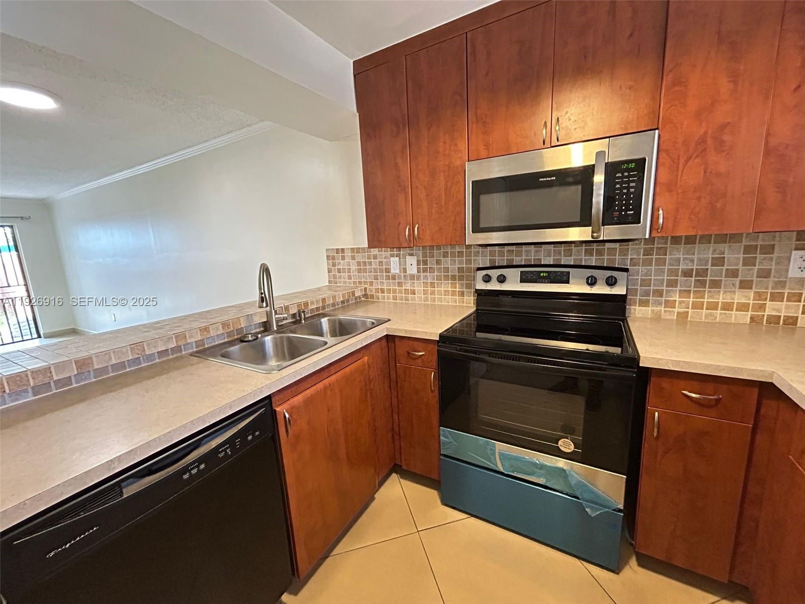 13444 Southwest 62nd Street, Unit 104F Miami, FL 33183 - Photo 7 of 40 a kitchen with stainless steel appliances a stove microwave and sink