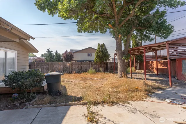 a backyard of a house with large trees and outdoor seating