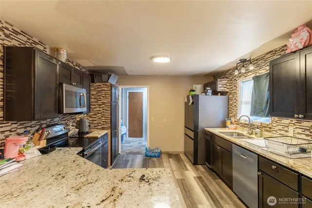 a kitchen with stainless steel appliances kitchen island granite countertop a sink stove and refrigerator