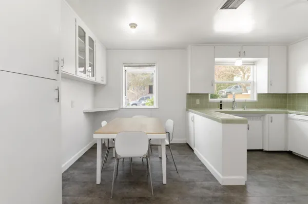 a kitchen with a white cabinets and table chair