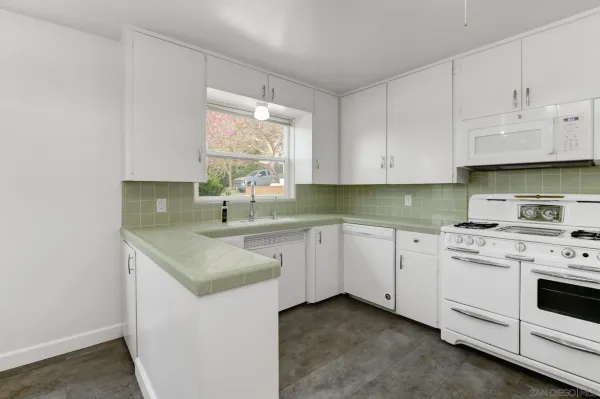 a kitchen with granite countertop white cabinets and white appliances