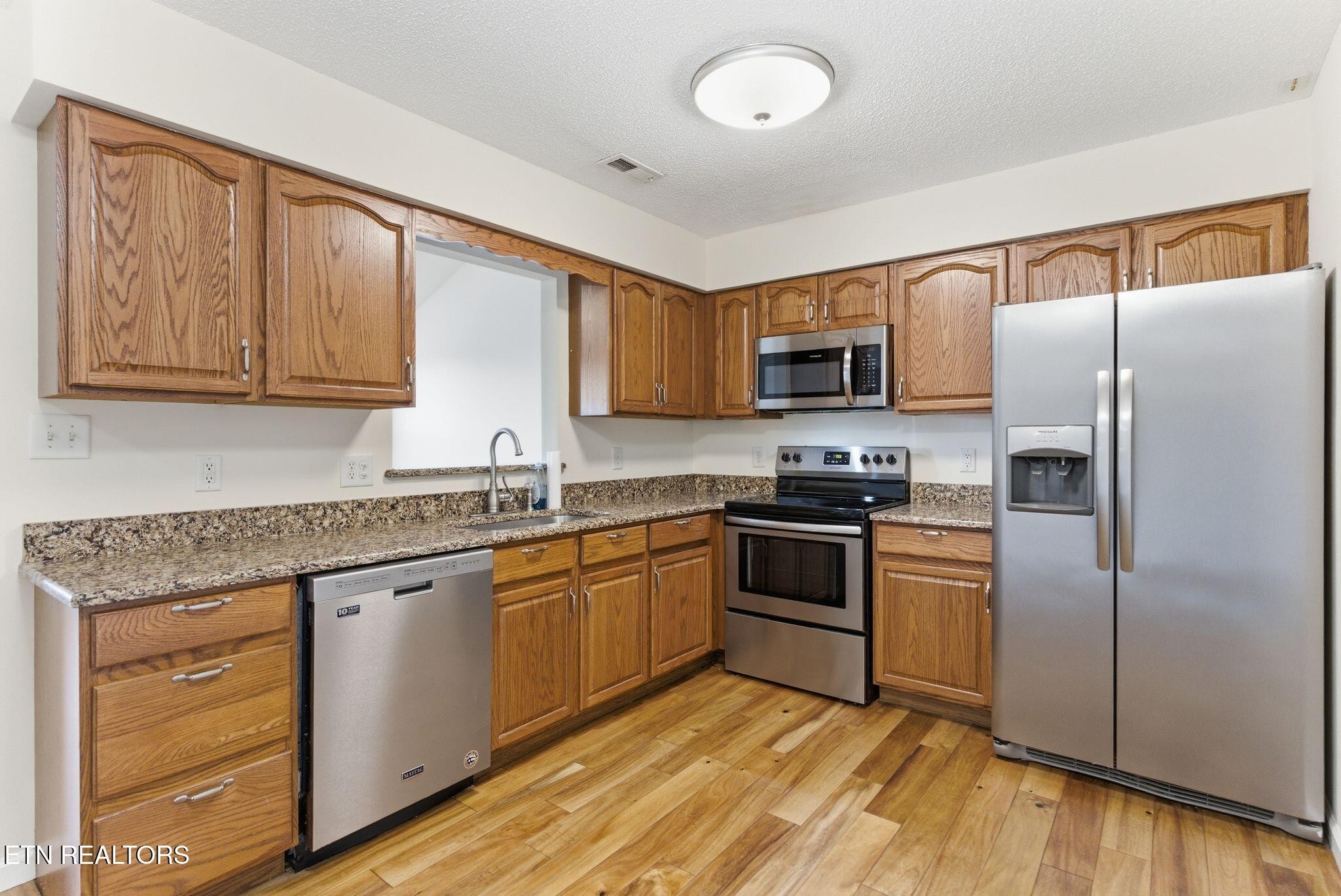 355 Hawthorne Oaks Way Powell, TN 37849 - Photo 12 of 31 a kitchen with granite countertop a refrigerator stove top oven and sink