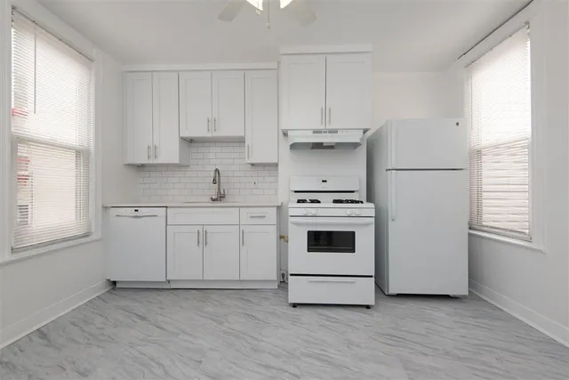 a kitchen with white cabinets white stainless steel appliances and sink
